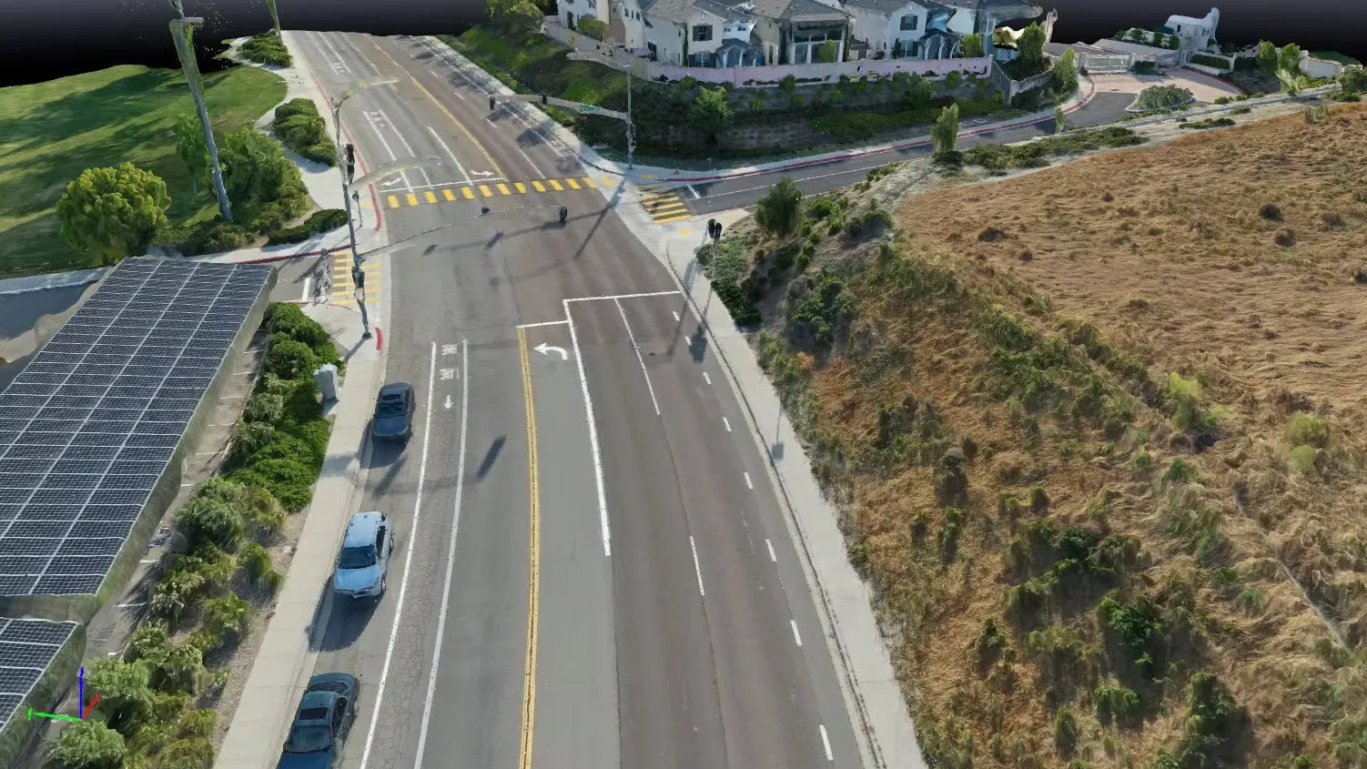 An aerial view of a divided road beside a hillside