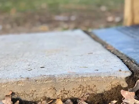 A raised edge where a concrete slab meets a driveway