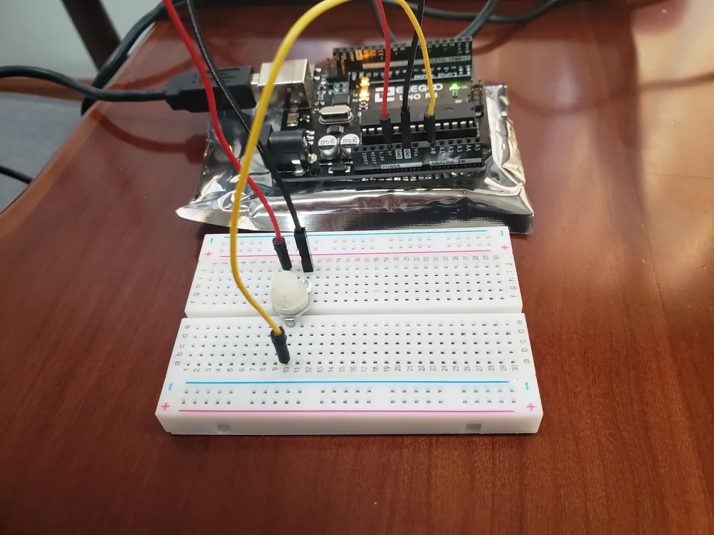 A circuit board wired to a breadboard on a desk