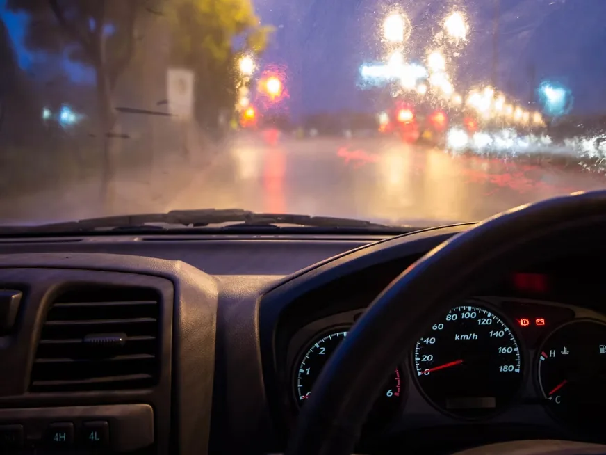 A lit street at night seen from the driver’s seat
