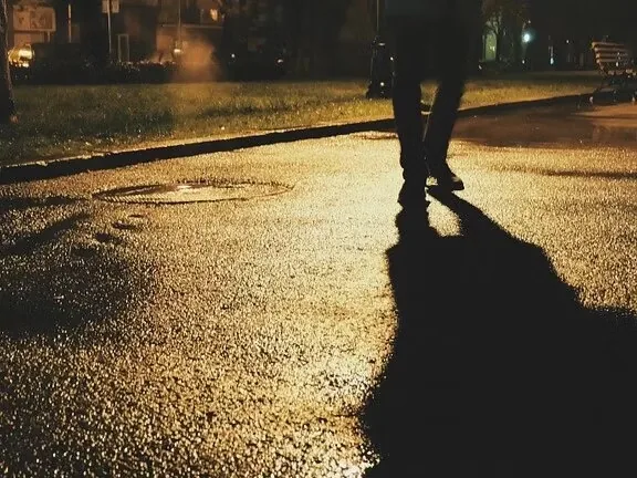 A pedestrian on a dark road lit by headlights